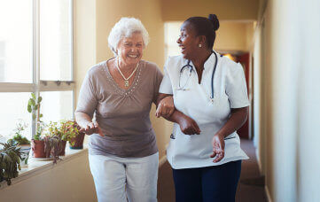 nurse helping elderly woman in walking