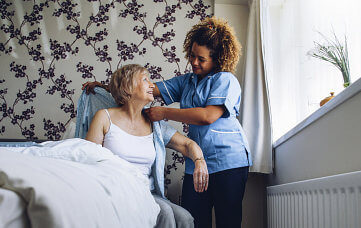 nurse helping elderly woman changing clothes