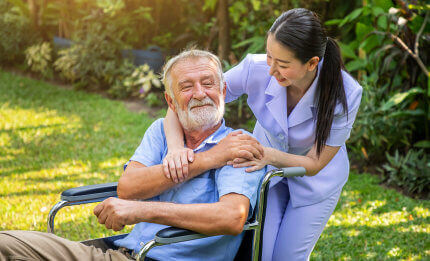 elderly man sitting in the wheelchair while comforting by the a nurse