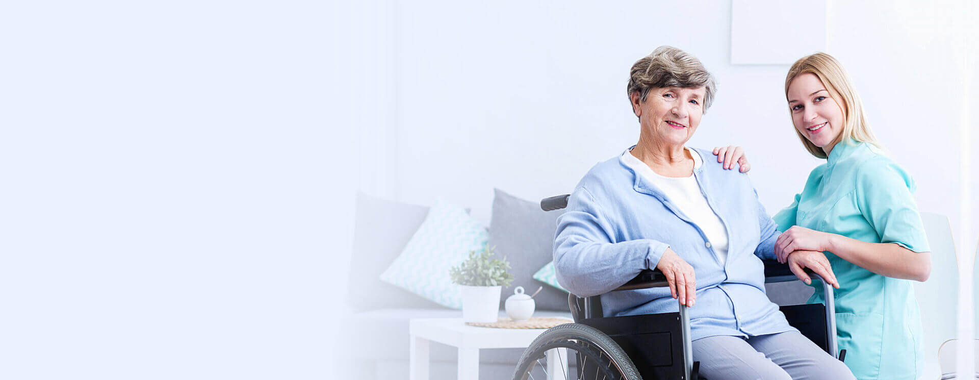 nurse smiling in the camera and elderly woman sitting in the wheelchair