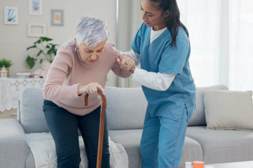 nurse helping elder woman to stand up